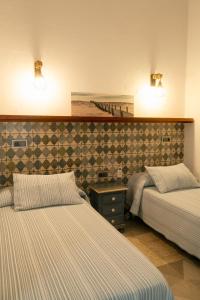 a bedroom with two beds and two lights on the wall at Montserrat Casa del Mar in Chipiona