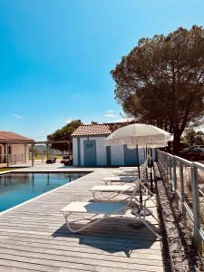 a row of lounge chairs and an umbrella next to a pool at Domaine de Barthas in Castelnau-Magnoac