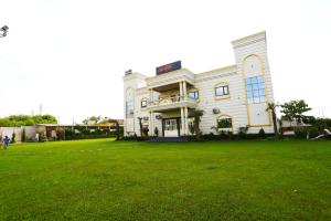 a large white building with a large grass field at The Prem Royal Resort & Hotel in Dāūd Khān