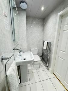 a white bathroom with a toilet and a sink at Sandyford Lodge in Glasgow