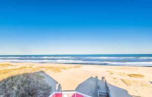 a red house on a beach with the ocean at Carolina Sunshine - Nags Head MP 16, Oceanfront, Pool, Hot Tub, Pets OK, Flex Stays in Nags Head