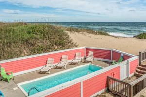 a swimming pool on the beach next to the ocean at Carolina Sunshine - Nags Head MP 16, Oceanfront, Pool, Hot Tub, Pets OK, Flex Stays in Nags Head