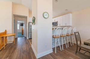 a kitchen and dining room with a clock on a wall at Carolina Sunshine - Nags Head MP 16, Oceanfront, Pool, Hot Tub, Pets OK, Flex Stays in Nags Head