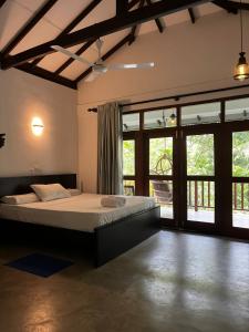 a bedroom with a bed in a room with windows at Augmented Kabalana in Ahangama