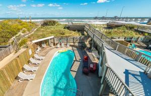 a swimming pool next to a beach and the ocean at Dune Diamond - Nags Head MP 16.5, Oceanfront, Elevator, Heated Pool, Hot Tub, Pets OK, Flex Stays in Nags Head