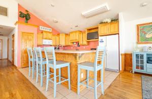 a kitchen with wooden cabinets and white stools at Dune Diamond - Nags Head MP 16.5, Oceanfront, Elevator, Heated Pool, Hot Tub, Pets OK, Flex Stays in Nags Head