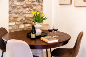 a wooden table with two glasses of wine and a book at Le Finestre su Villa d'Este in Tivoli