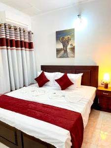 a bedroom with a large bed with red and white pillows at Nishi Villa in Negombo