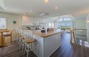 a kitchen with white cabinets and a bar with chairs at Shell Town – Nags Head MP 16, Ocean View, 360 Yds to Beach, Pool, Hot Tub, Flex Stays in Nags Head