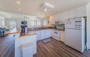 a kitchen with white cabinets and a white refrigerator at Shell Town – Nags Head MP 16, Ocean View, 360 Yds to Beach, Pool, Hot Tub, Flex Stays in Nags Head
