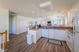 a large kitchen with white cabinets and wooden floors at Shell Town – Nags Head MP 16, Ocean View, 360 Yds to Beach, Pool, Hot Tub, Flex Stays in Nags Head +44 photos