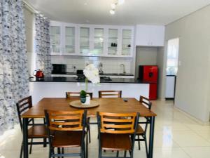 a dining room table with chairs and a kitchen at Logo Luxury Guesthouse in Windhoek