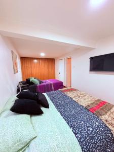 a bedroom with two beds and a flat screen tv at Casa Las Condes, steps from Manquehue Metro in Santiago