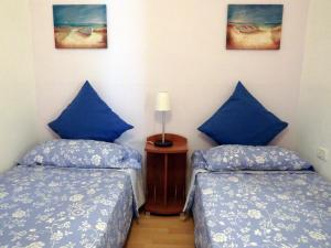 two beds in a room with blue pillows at La casa de Emma in Los Campitos