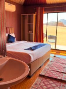 a bedroom with a bed and a tub and a window at Luxury Camp Wadi Rum in Disah