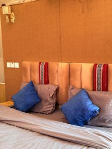 a bed with blue and brown pillows on it at Luxury Camp Wadi Rum in Disah