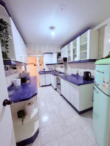 a large kitchen with white cabinets and blue counter tops at Casa Las Condes, steps from Manquehue Metro in Santiago