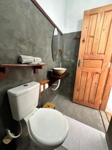 a bathroom with a toilet and a wooden door at Vila Manguita Suíte Manguita in São Gonçalo do Amarante