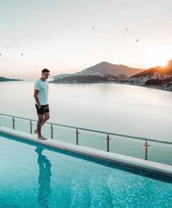 Ein Mann steht am Rand eines Schwimmbeckens in der Unterkunft Hotel Ponta Nova in Budva