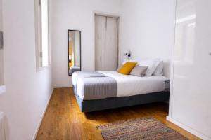 a white bedroom with a bed with a mirror at Oporto City View - Santa Catarina in Porto