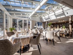 a restaurant with white tables and chairs and windows at Hotel Rita in Längenfeld