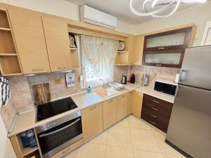 a kitchen with wooden cabinets and a stainless steel refrigerator at Villa Mickey in Hanioti