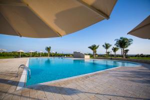 a swimming pool with an umbrella and palm trees at Casal Sikelio in Cassibile