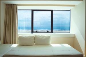 a white bed sitting in front of a window at Sweet Atlantic Hotel & Spa in Figueira da Foz