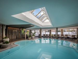 a large swimming pool in a building with a skylight at Hotel Rita in Längenfeld