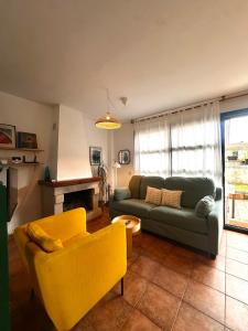 a living room with a green couch and yellow chairs at Cala Tatina in Celorio