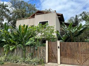 a house behind a fence with a wooden gate at Casa do Rio in Morretes