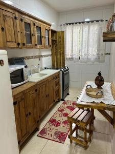 a kitchen with wooden cabinets and a sink and a table at Casa do Rio in Morretes