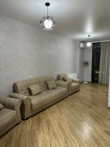 a living room with a large couch and wooden floors at Ander Tower in Stantsiya Batumi-Passazhirskaya