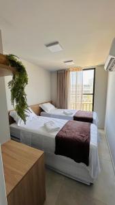 two beds in a hotel room with a window at Brisa Rooftop Vistamar -Apartamento à beira mar com jacuzzi in Luis Correia +65 photos