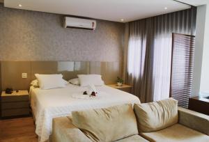 a bedroom with a white bed and a couch at Hotel Canoeiros in Pirapora +52 photos