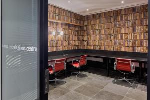 a library with red chairs and a table and books at Radisson Blu Hotel, London Canary Wharf East in London +99 photos