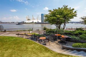 a patio with tables and chairs next to a river at Radisson Blu Hotel, London Canary Wharf East in London