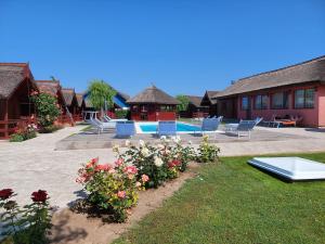 a resort with a swimming pool and some chairs and flowers at La Tavi casute tip camping in Murighiol