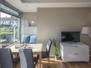 a dining room with a table and chairs and a television at Strandburg "Tiefblau" 01 b in Burgtiefe auf Fehmarn 