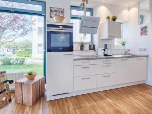 a kitchen with white cabinets and a large window at Strandburg "Azurblau" 01 c in Burgtiefe auf Fehmarn 
