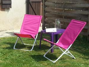two pink chairs and a purple table in the grass at Gîte Tucolet in Hinx