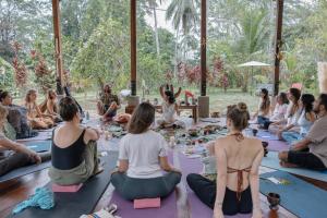 a group of people sitting on the floor in a yoga class at Salvia Madre Hotel Boutique in Guachaca