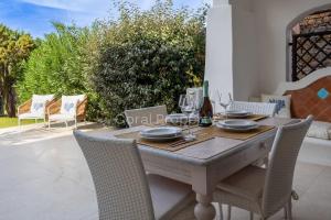 a wooden table and chairs on a patio at Suite Rea Beachfront - Giardino & Spiaggia Privata - by Coral Property in Porto Cervo
