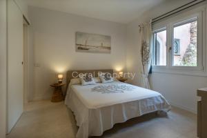 a white bedroom with a bed and a window at Suite Rea Beachfront - Giardino & Spiaggia Privata - by Coral Property in Porto Cervo