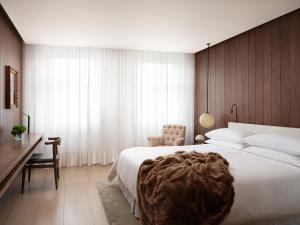 a bedroom with a large white bed and a desk at The London EDITION in London