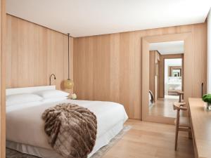 a bedroom with a white bed and a wooden wall at The London EDITION in London