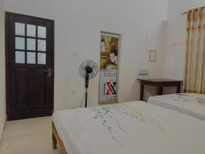 a bedroom with two beds and a fan next to a door at Nathalie Villa in Anuradhapura +4 photos