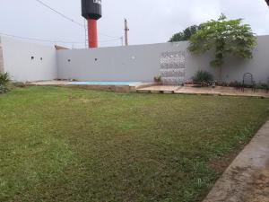 a backyard with a white wall and a swimming pool at Pousada santa Clara in Matão +4 photos
