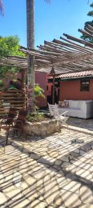a patio with two chairs and a wooden pergola at Catavento Flats e Suítes in Maresias