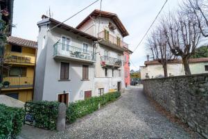 a white building with a balcony next to a wall at Azure Comfort Studio in Bellagio